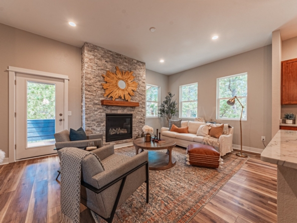 Great room with couches, fireplace, and deck door.